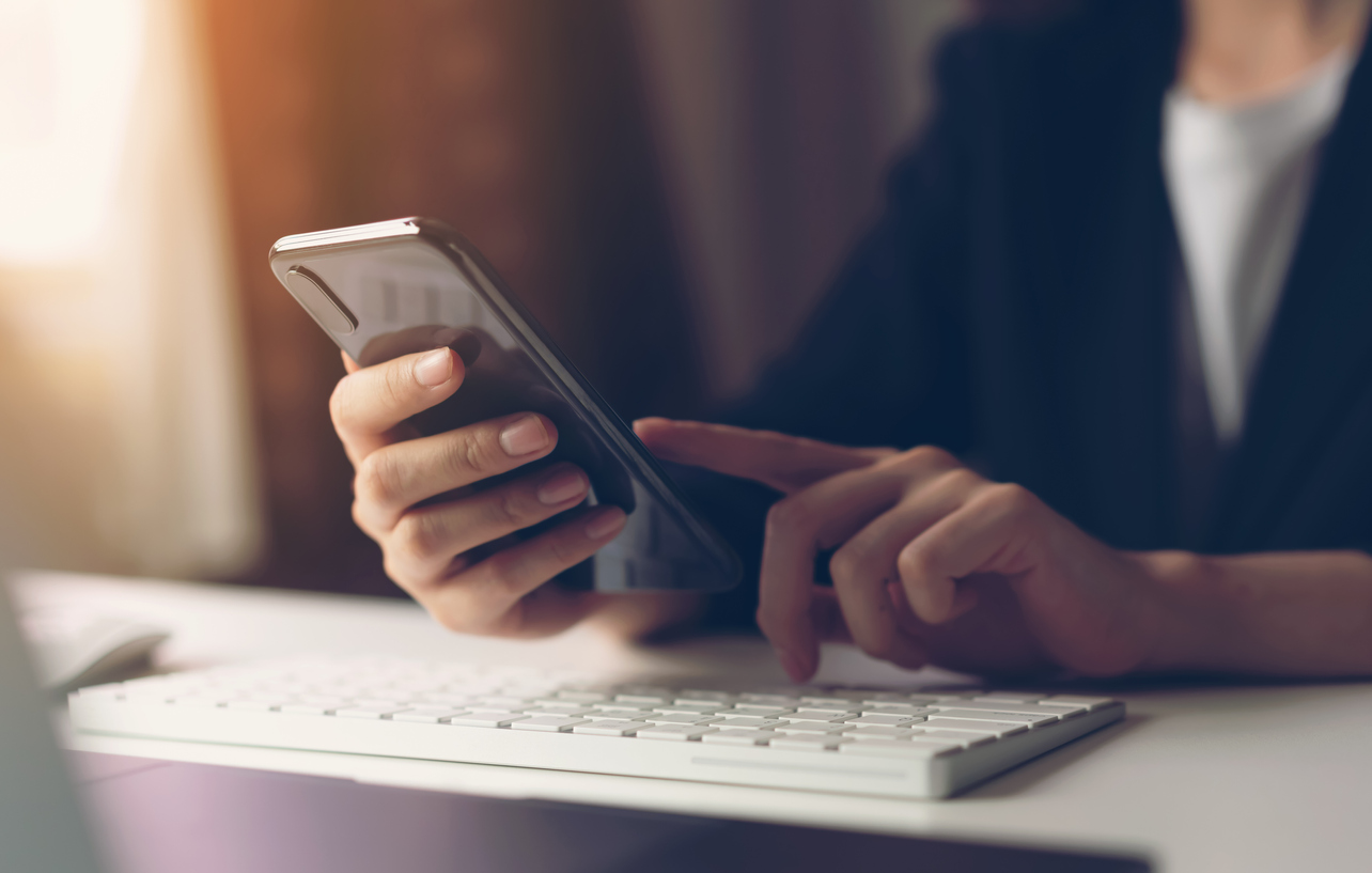 Woman using smartphone in home office