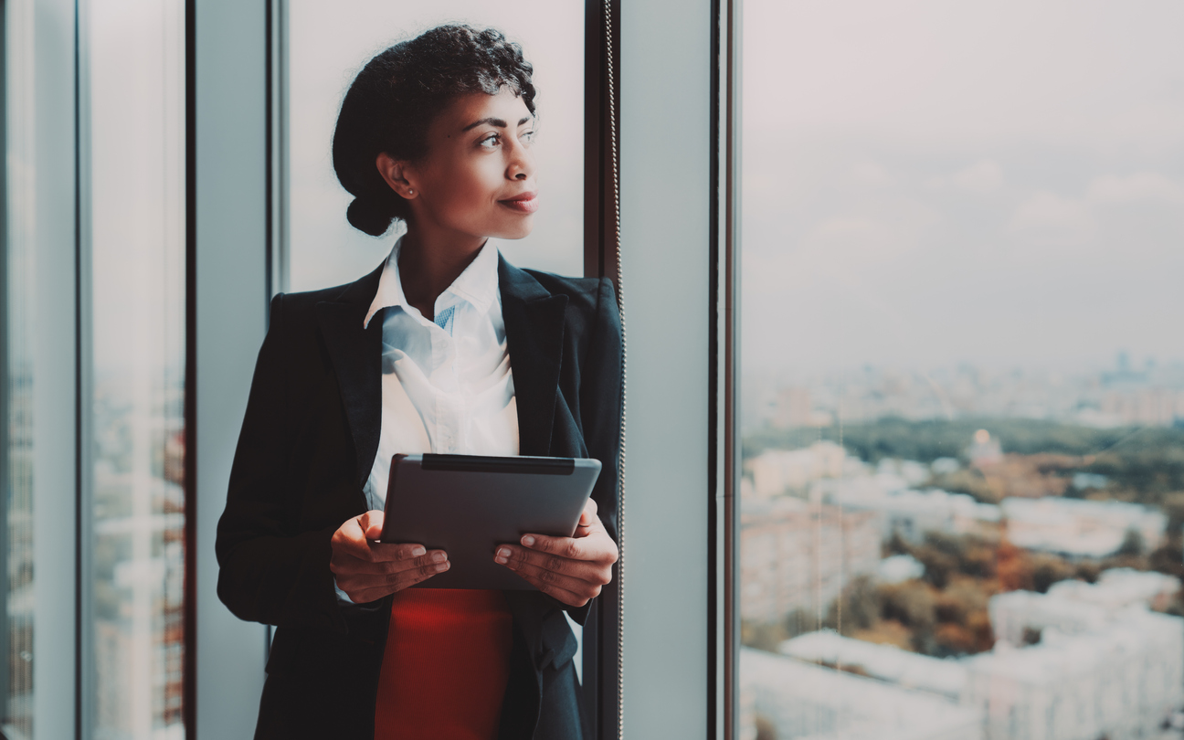 Black businesswoman with tablet standing at a window