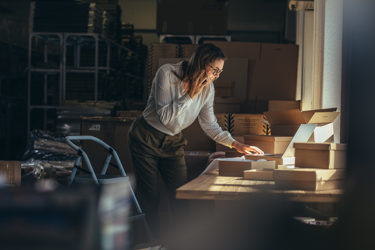 Businesswoman in warehouse taking orders on phone