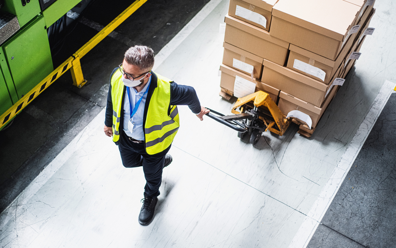 Masked man moving boxes in warehouse