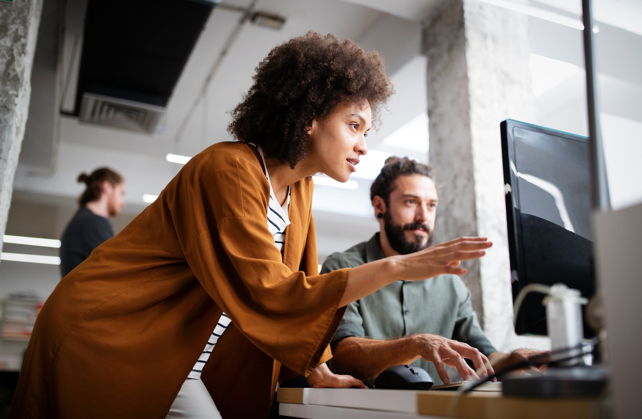 Two corporate employees reviewing data on a computer monitor