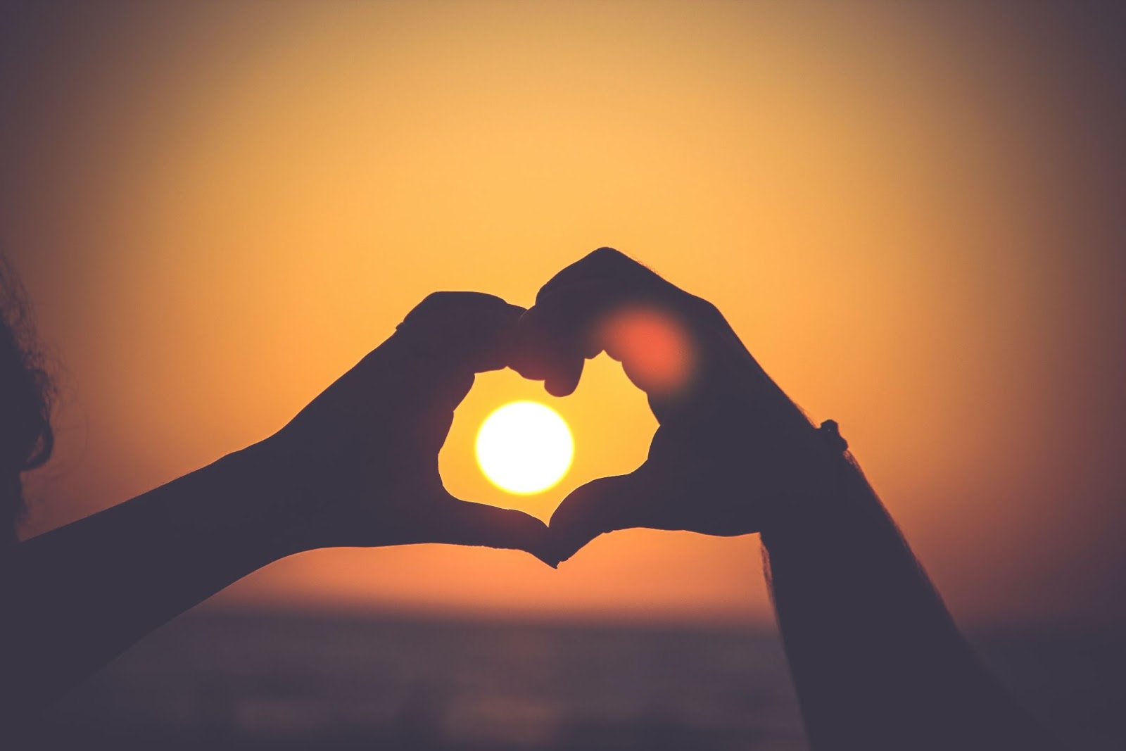 Hands outlining the sun with a heart image