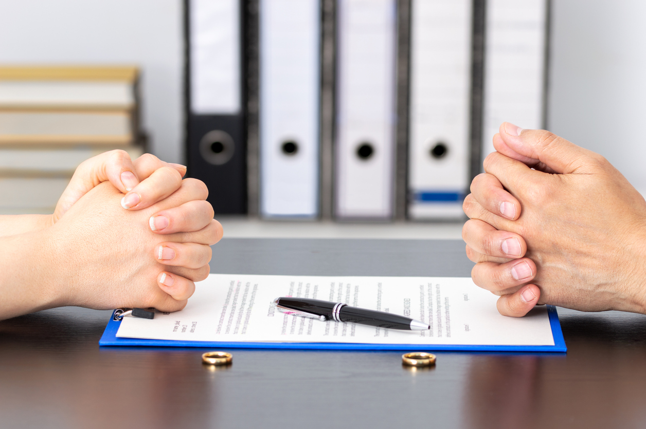 Hands of wife and husband signing divorce documents or premarital agreement at the lawyer's office