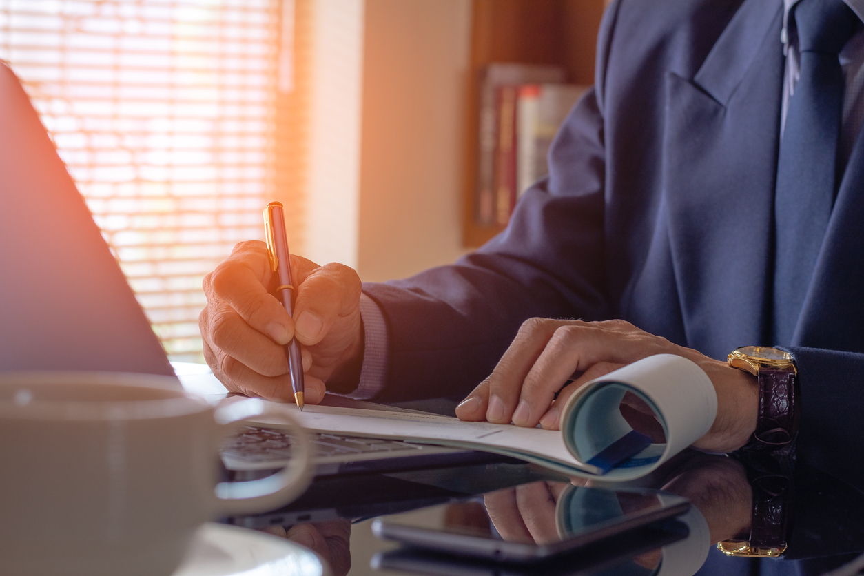 Businessman hand writing and signing white empty bank checkbookm Payment by check, paycheck, payroll , cheque sign conceptual.