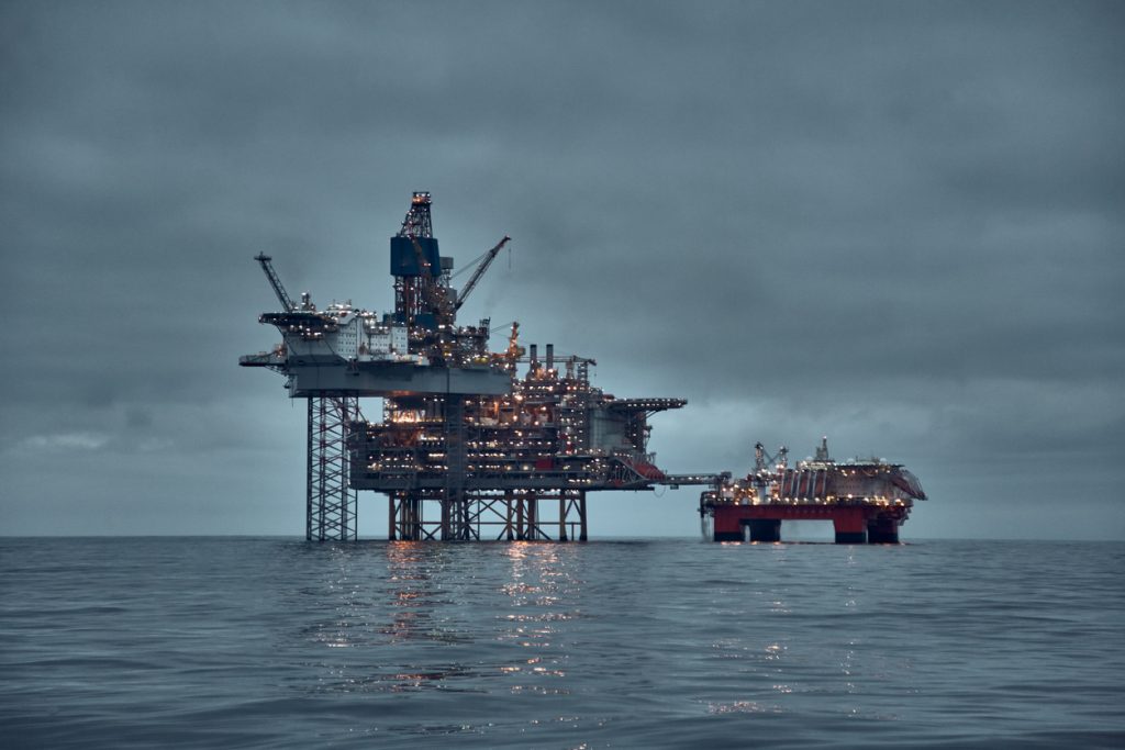 oil and gas platform, jack up rig in the sea at dusk with dark sky and clear water surface.