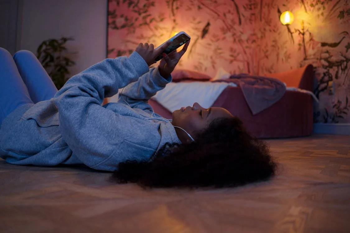 A woman lying on her bed looking at her phone.