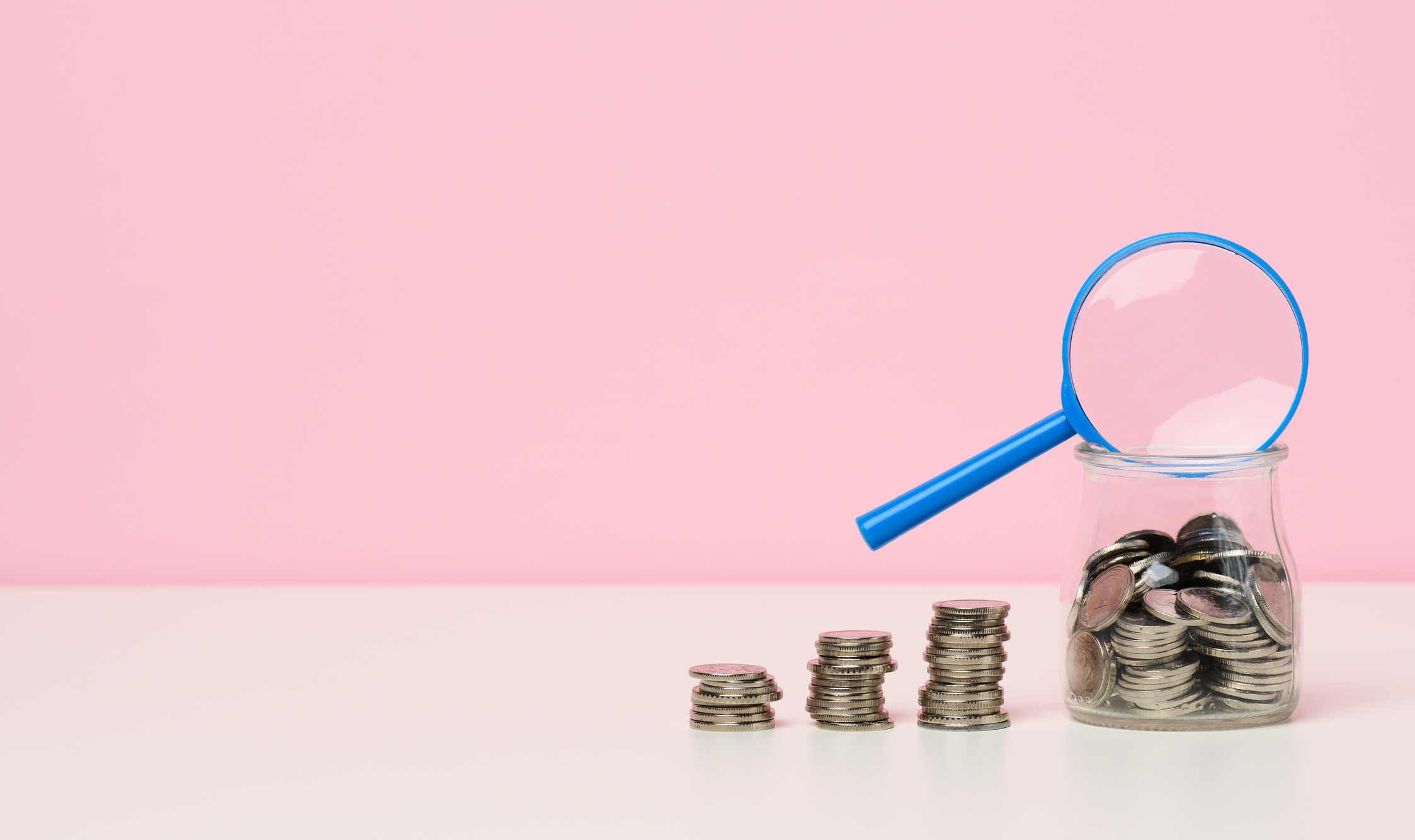 blue magnifier and white coins on the table. income growth concept, high percentage of investment. search for new sources of income, subsidy