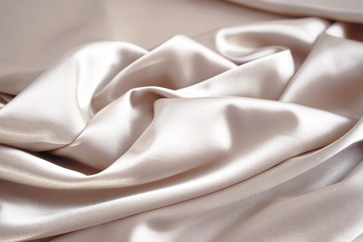 light pale brown silk satin. pink beige color. luxury elegant background. creases in fabric.