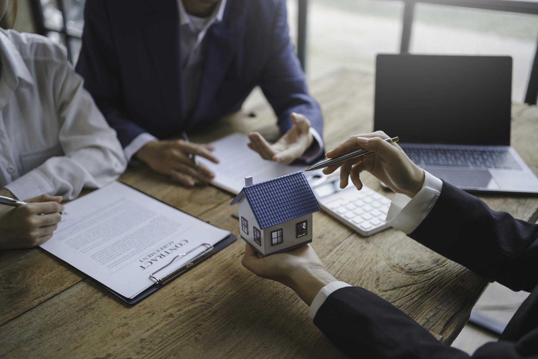 real estate agents offer customers a sample house to view and explain in more detail after agreeing to a contract to buy and sell the home, such as a mortgage, insurance. couple sign a house purchase contract.