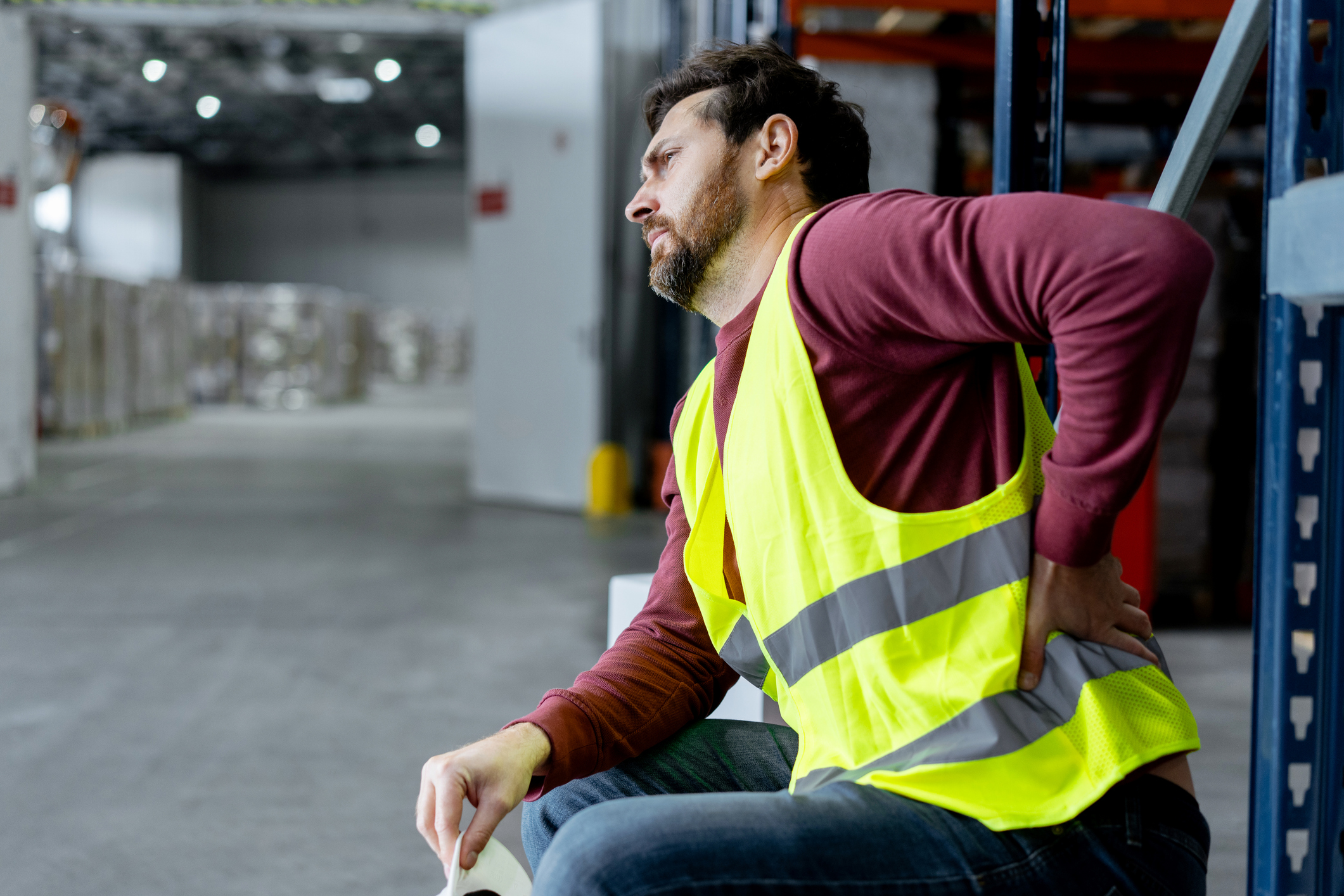 upset, tired, overworked man, foreman wearing workwear touching back, having pain, spasm