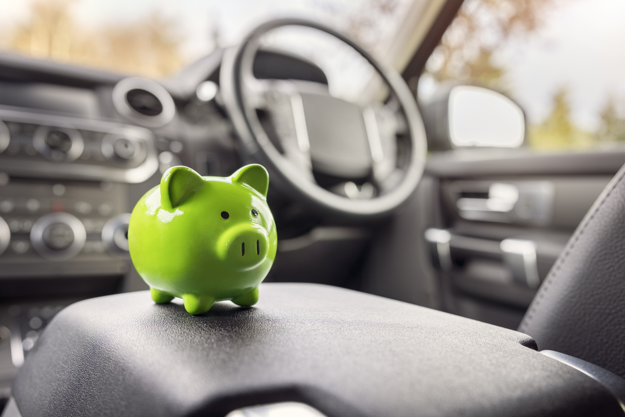 green piggy bank money box inside car, vehicle purchase, insurance or driving and motoring cost