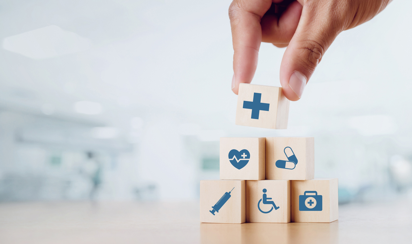 close up man hand arranging wood block with healthcare medical icon on hospital background. health care and health insurance concept.